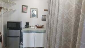 A compact kitchenette with a microwave, coffee maker, and a small refrigerator. There are framed pictures on the wall and a patterned curtain. - 3 Minutes Drive to Famous Magens Bay Beach (St Thomas)