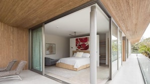 Un dormitorio moderno con una cama grande, vistas al exterior y un balcón con una silla.
