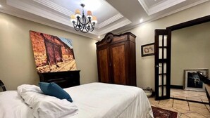Ein Schlafzimmer mit einem Bett, einem Holzschrank, einem Bild an der Wand und einer Kronleuchter.