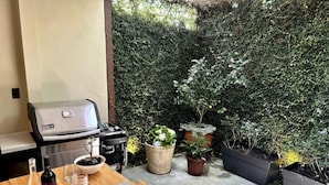 A patio with a grill, dining table, and potted plants. - Elegant Escalante Home (San José)