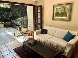 Un salon avec un canapé beige, une table basse et un tableau encadré accroché au mur.