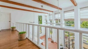 Een ruim balkon met houten balken, witte leuningen en planten in potten.