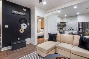 Relax in this stylish living space with a comfortable sofa, ottoman, and modern kitchen area.