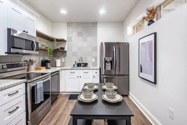 Enjoy cooking in this well-equipped kitchen with stainless steel appliances, a dining table, and a tiled backsplash.