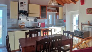 A kitchen with wooden beams, a dining table with chairs, a microwave, and a sink. - A TERRACE IN THE GREEN apartment surrounded by nature, away from the hustle and bustle  (Lombardia)