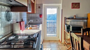 A kitchen with a gas stove, sink, and a view of a balcony. - A TERRACE IN THE GREEN apartment surrounded by nature, away from the hustle and bustle  (Lombardia)
