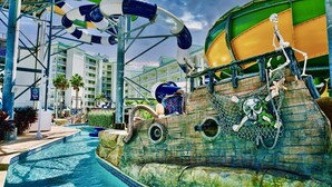 Parque acuático con temática pirata, que incluye una gran estructura de barco, toboganes y una piscina.