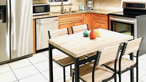Una cocina moderna con armarios de madera, electrodomésticos de acero inoxidable y un comedor con mesa y sillas de madera.