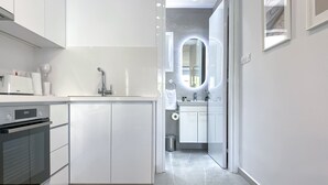 A modern kitchen with white cabinetry, a built-in oven, and a countertop with a coffee machine. - Phaedrus Living: Limnaria Luxury Flat Vine 121 (Paphos)