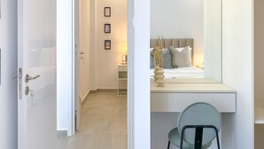 A modern bedroom with a bed, bedside table, and a chair. - Phaedrus Living: Limnaria Luxury Flat Vine 121 (Paphos)