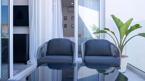 A balcony with two grey cushioned chairs, a potted plant, and a glass table. - Phaedrus Living: Limnaria Luxury Flat Vine 121 (Paphos)