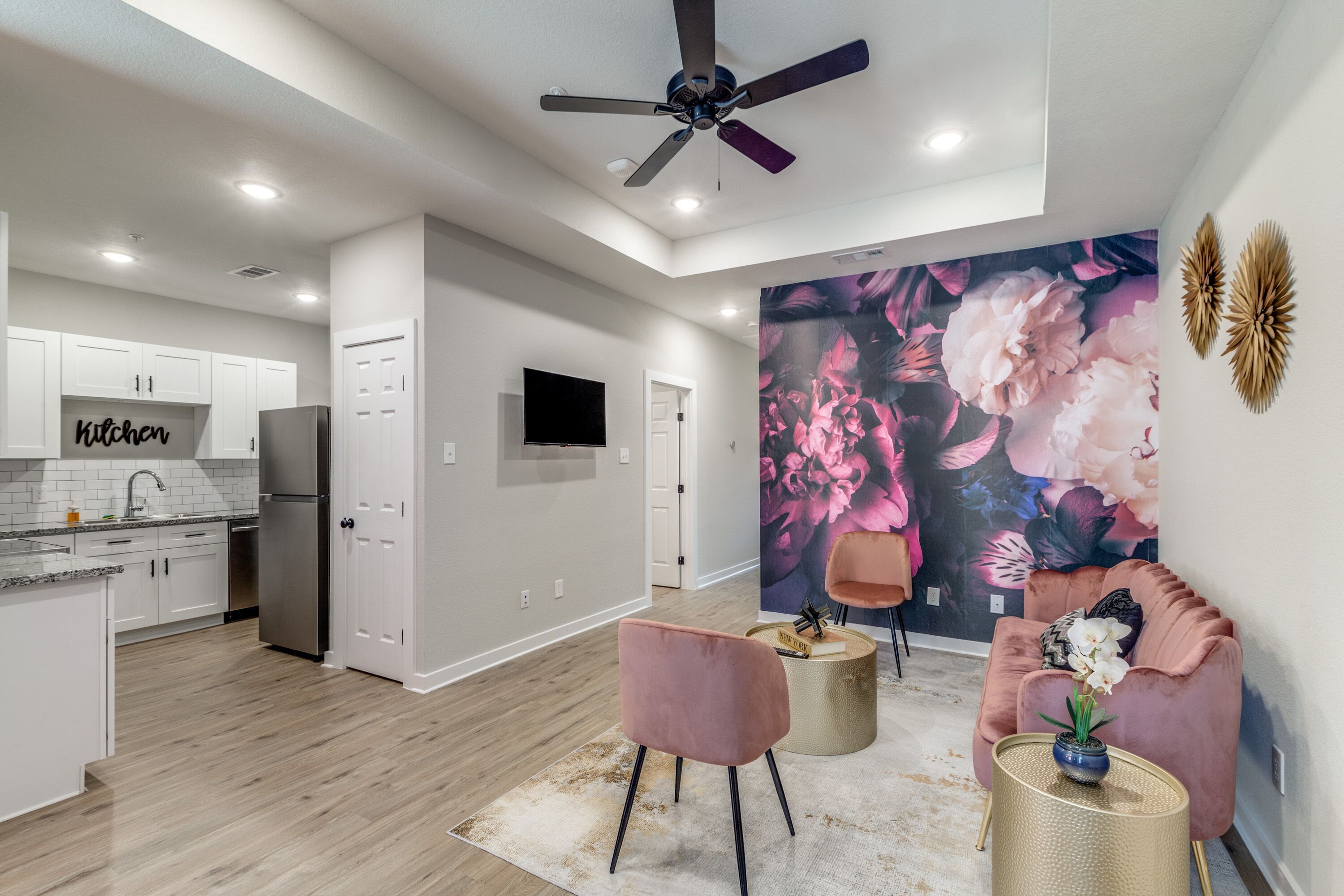 A modern kitchen with white cabinets, a stainless steel refrigerator, and a ceiling fan.