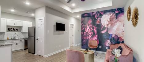 A modern kitchen with white cabinets, a stainless steel refrigerator, and a ceiling fan.