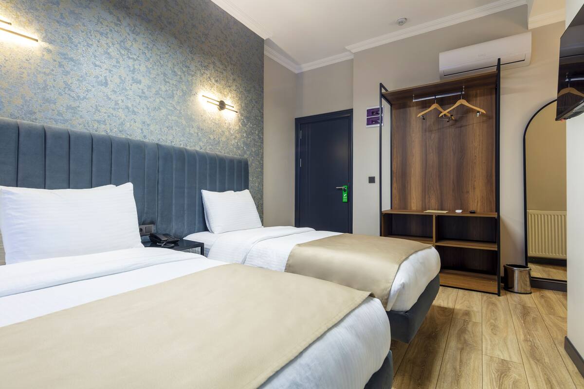 A hotel room with two beds, a wardrobe, and a mirror.