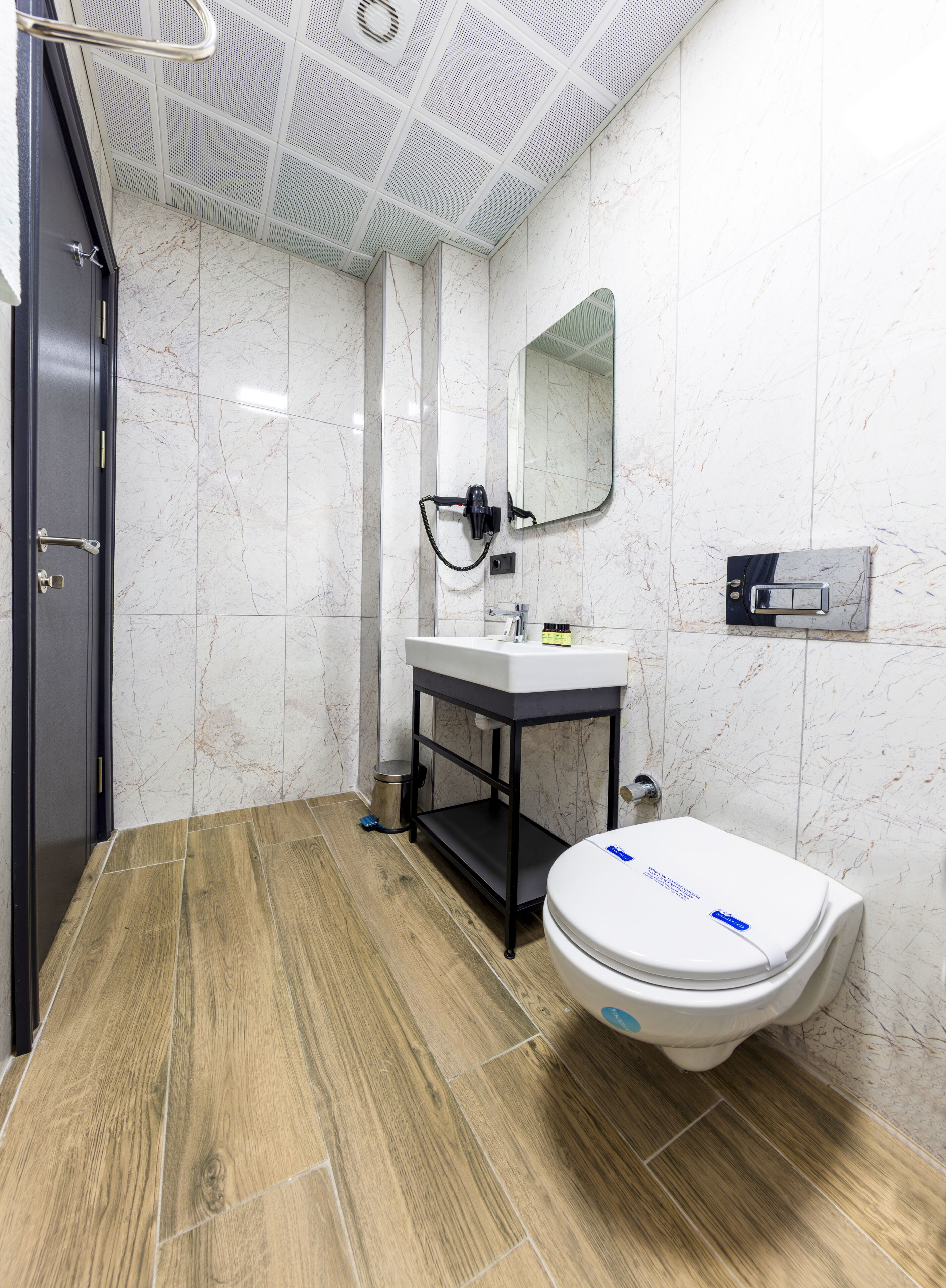 A modern bathroom with a toilet, sink, and mirror.