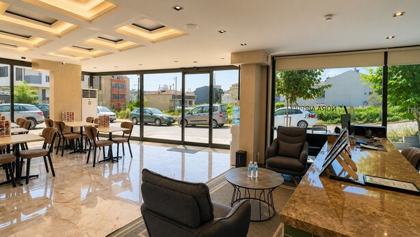 A hotel lobby with a seating area, a reception desk, and large windows offering a view of the street. - Nora Airport Hotel Istanbul  (Arnavutköy)