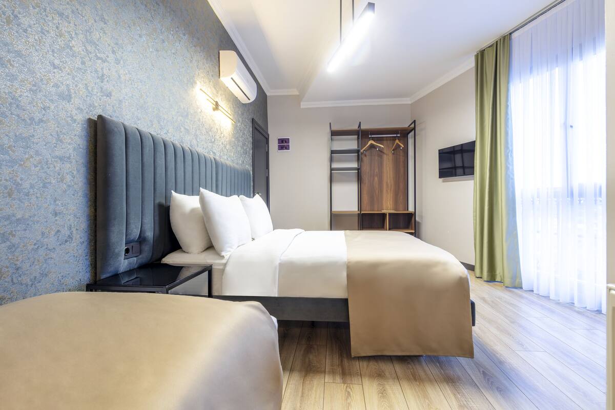 A hotel room with a large bed, a bedside table, a wardrobe, and a TV mounted on the wall.