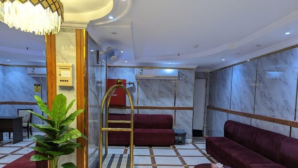 Un vestíbulo de hotel con mostrador de recepción, zona de estar y mesa de información.