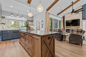 Una cocina amplia con una isla grande, armarios de madera e iluminación colgante.