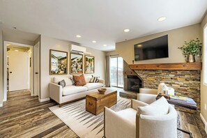 A modern living room with a fireplace, a sofa, a coffee table, and a TV mounted on the wall. - The Ski Lift Loft 31 (Park City)
