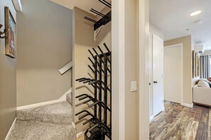 A hallway with a coat rack, a door, and a living area with a sofa.