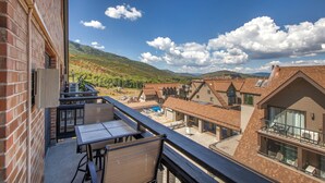 Un balcon avec une table et des chaises, donnant sur un quartier résidentiel avec des maisons et une montagne en arrière-plan.