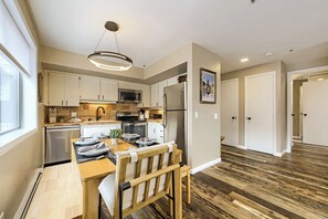 A modern kitchen with white cabinets, stainless steel appliances, and a dining area with a wooden table and chairs.