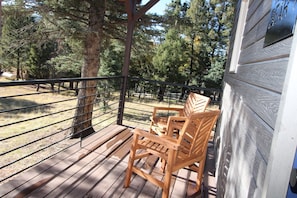 Relax on the deck with a view of the surrounding forest and grassy field.
