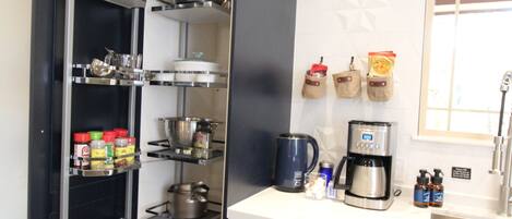 Una cocina moderna con lavavajillas integrado, cafetera y especiero.