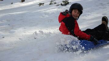 A child sledding down a snowy slope.