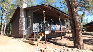 A cabin with a stone chimney, wooden steps, and a covered porch. - Aspen Springs Angel fire (Angel Fire)