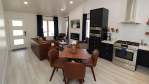 A modern kitchen with a dining area, featuring a central island, built-in oven, and a large stove. - Aspen Springs Angel fire (Angel Fire)