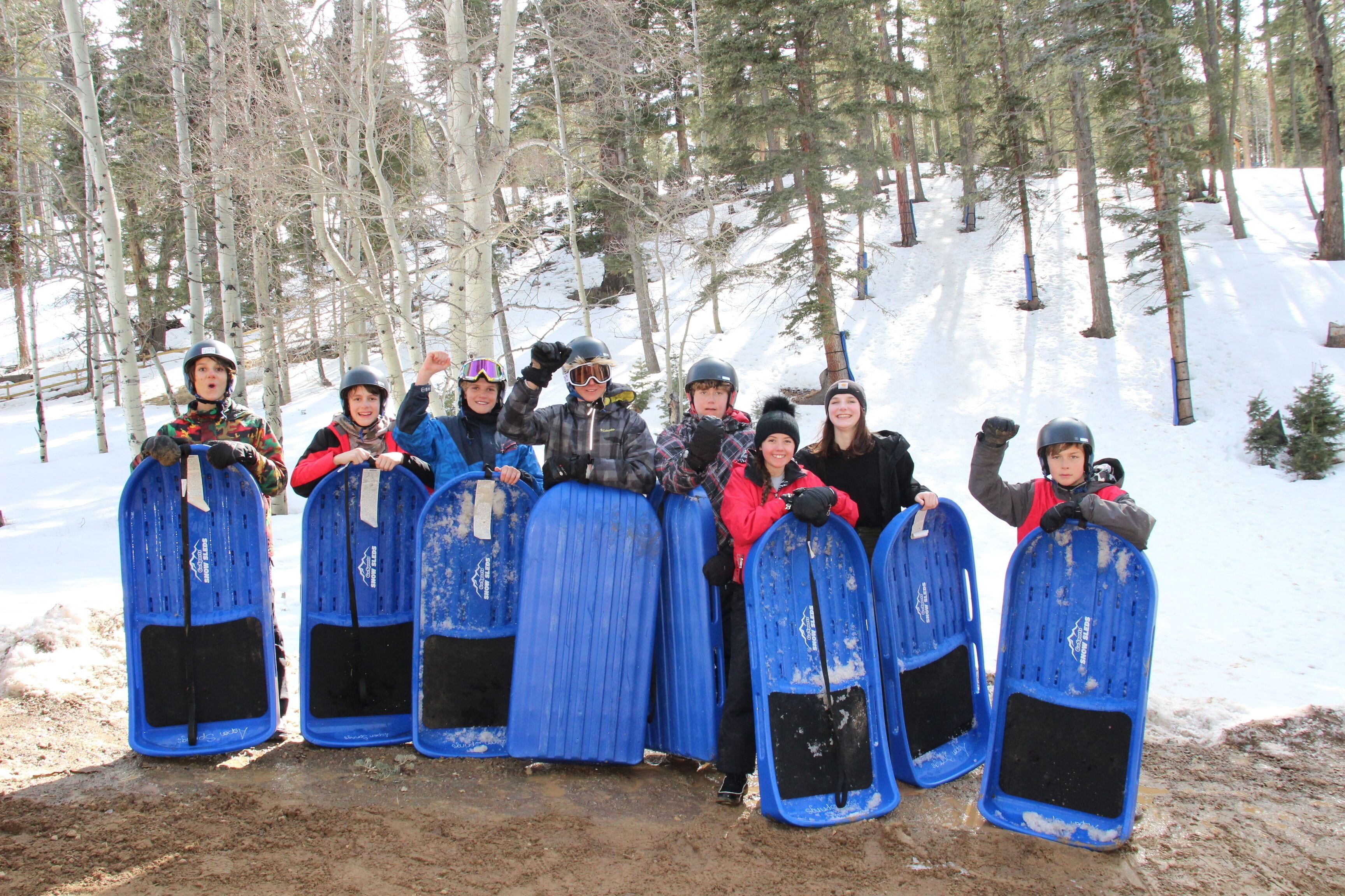Un groupe de personnes tenant des planches de snowboard bleues dans une forêt enneigée.