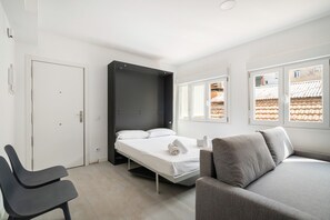 A modern bedroom with a bed, a sofa, a chair, and a wardrobe. - apartamentos reformados en madrid rio de alquiler temporal (Madrid)