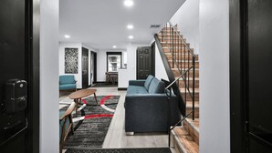 A modern living room with a sofa, coffee table, and a staircase leading to another level. - Escape to This Gorgeous new Wilton Manors Villa (Wilton Manors)