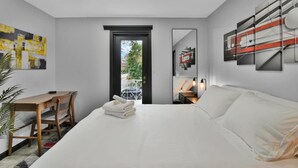 Een moderne hotelkamer met een groot bed, een bureau en een stoel. Er is een deur naar een balkon met uitzicht.