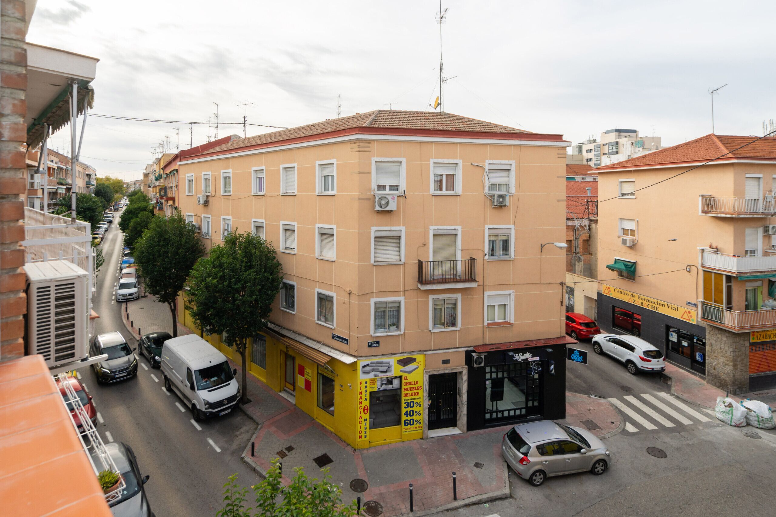 Un edificio de varios pisos con fachada amarilla, varios balcones y un local comercial en la planta baja.