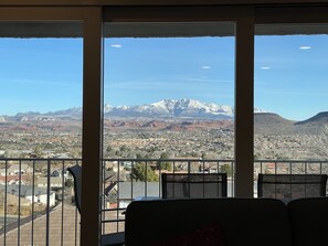 Relax in a room with a panoramic mountain view, featuring a seating area and table for dining or unwinding.