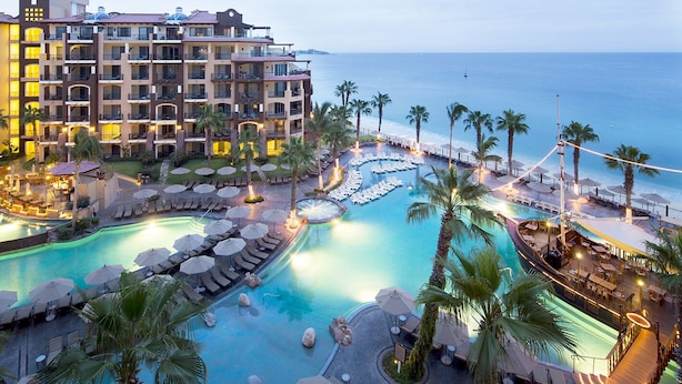 A resort with multiple swimming pools, palm trees, and a large building with balconies overlooking the water. - Spectacular Ocean View Suite for the Holidays on the Beach!  (Cabo San Lucas)