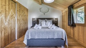 A wooden cabin-style bedroom with a bed, towels, and a deer head decoration. - Chalet Castor Gorgeous ski-in/ski-out 4 bedroom chalet in Les Houches (Les Houches)