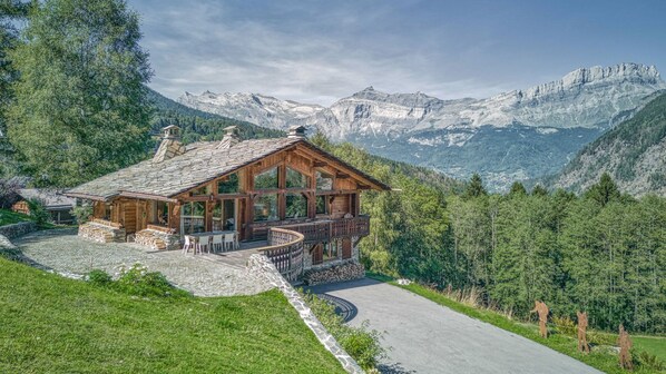 A wooden chalet with a stone roof, a balcony, and a stone pathway leading to the entrance. - Chalet Castor Gorgeous ski-in/ski-out 4 bedroom chalet in Les Houches (Les Houches)