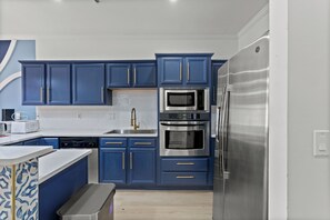 A modern kitchen with blue cabinets, stainless steel appliances, and a white countertop.