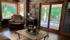 A cozy living room with a leather sofa, a wooden coffee table, and a large window offering a view of the outdoors.