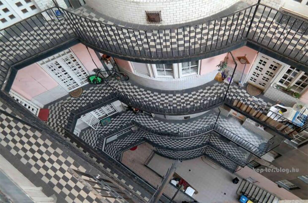 A multi-level building with a checkered floor pattern, balconies, and a central courtyard.