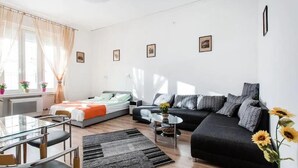 Ein modernes Wohnzimmer mit einer Couch, einem Glastisch und einem Bett.