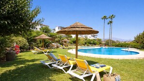Zona de piscina amb gandules, ombrel·les i una piscina.
