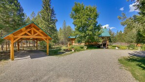 A wooden gazebo with a gravel path leading to it, surrounded by trees and a clear sky.