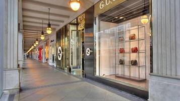 A corridor with storefronts, including a Gucci store with a display of handbags.