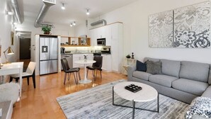 Una sala moderna con un sofá gris, una mesa de centro y un comedor con sillas y una mesita.