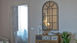 Un salon comprenant un canapé, une console en bois avec des tiroirs, un miroir et une plante en pot.